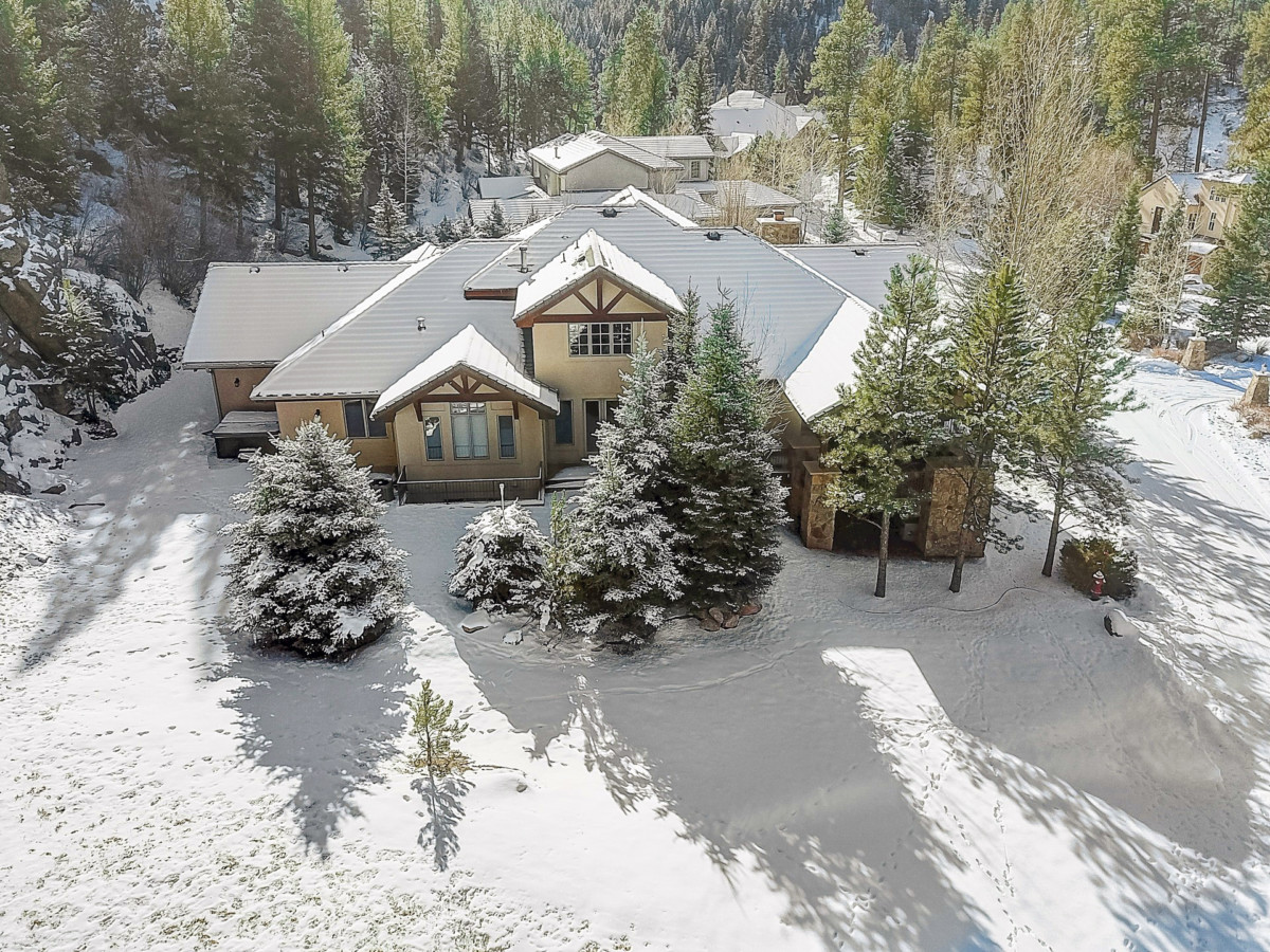 large house on a property with snow in the front yard and snow covered trees after a winter storm