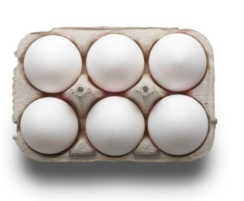 High angle studio shot of six white eggs in a box isolated on white background