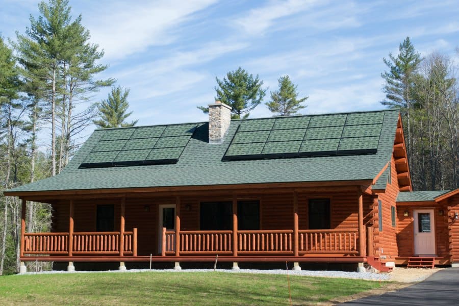Sistine Solar’s completed SolarSkin installation on a Katahdin log cabin. The company’s SolarSkin panels seamlessly blend in with the cabin’s green roof. | Photo Courtesy of Sistine Solar