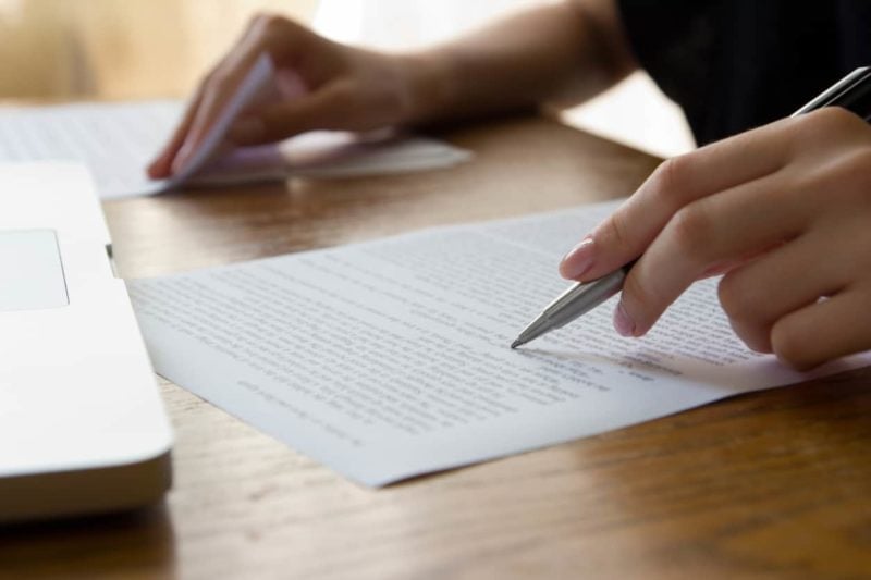 Hand holding a pen and writing a real estate offer letter