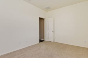 Empty bedroom with door and wall-to-wall carpet