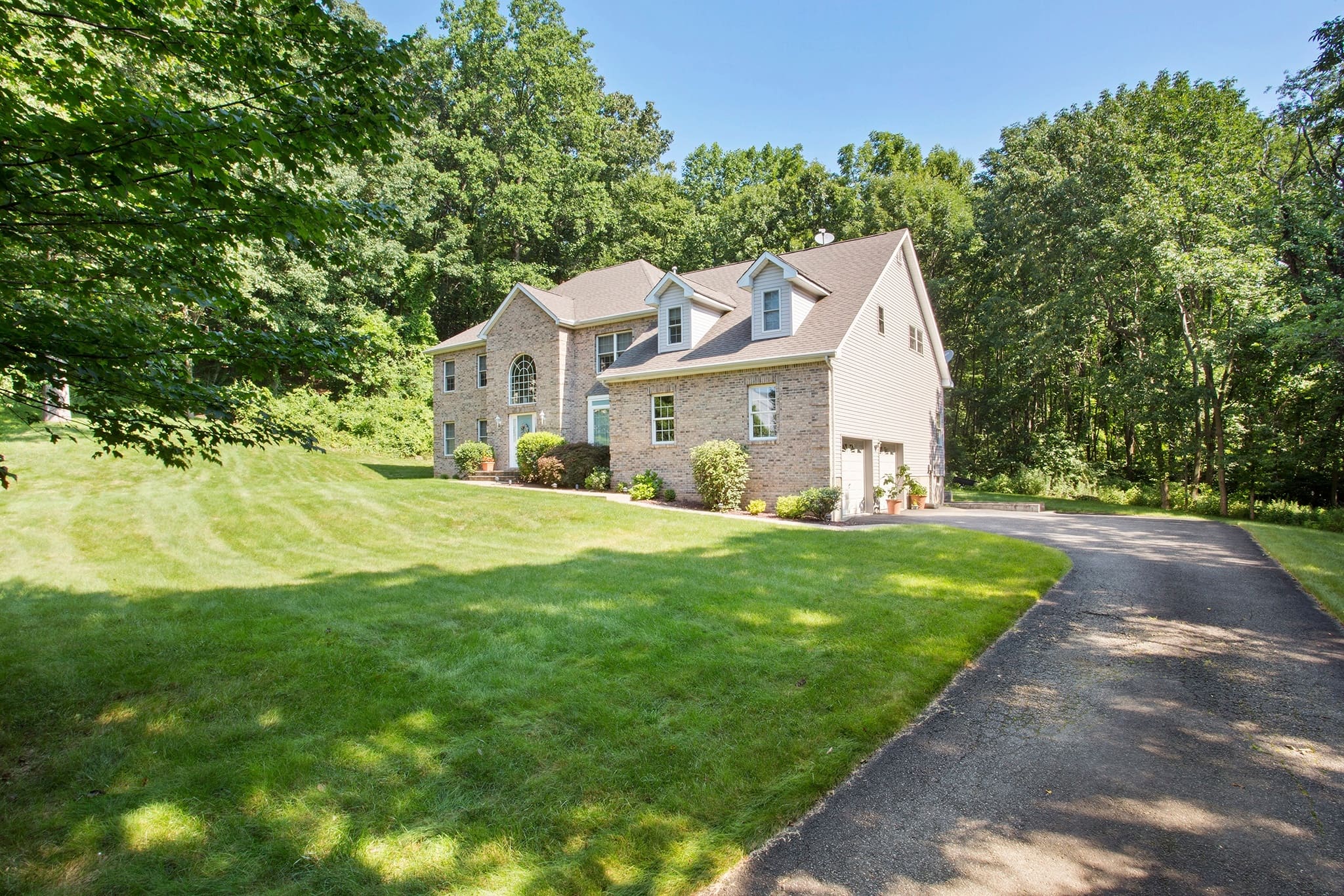 Older, traditional home with asphalt driveway leading up to the garage