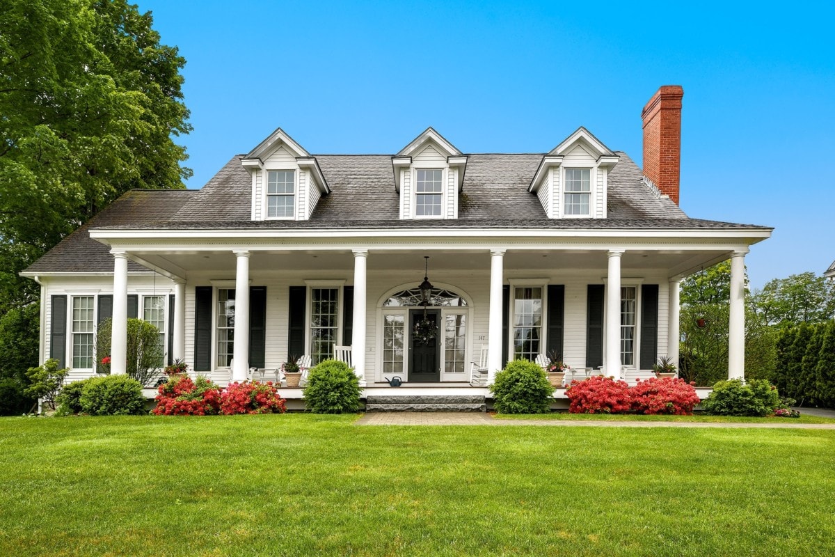 Single-story white cape-cod home with large lawn and front porch