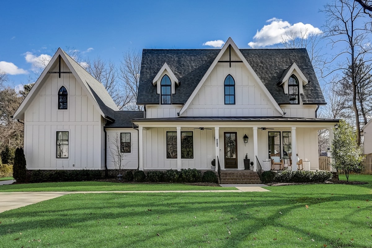 Two story white farmhouse-style home with a large lawn and black trim