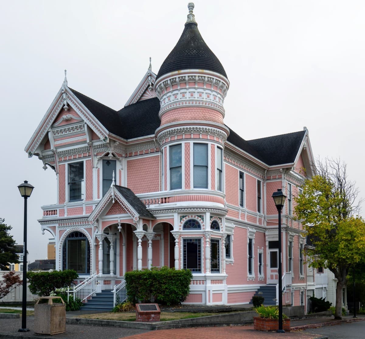 Two-story, pink victorian style home with white trim and round tower