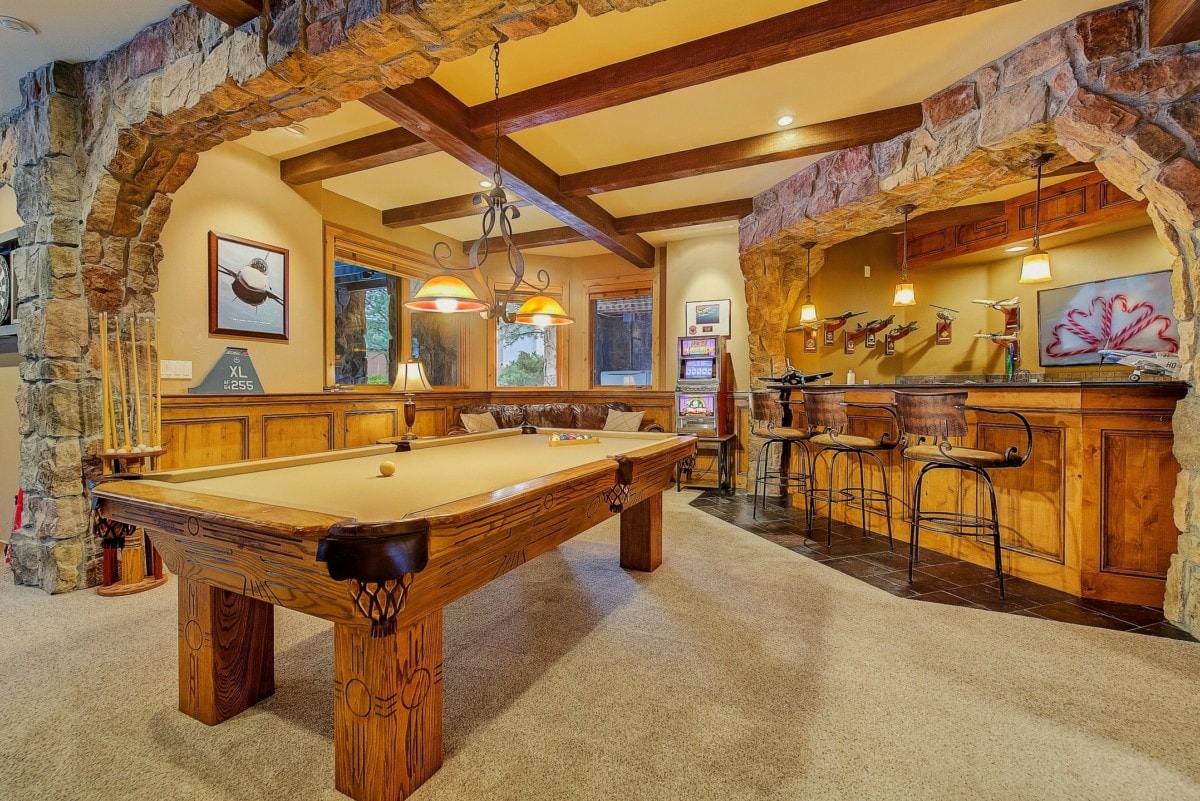 carpeted finished basement with stone details and a pool table