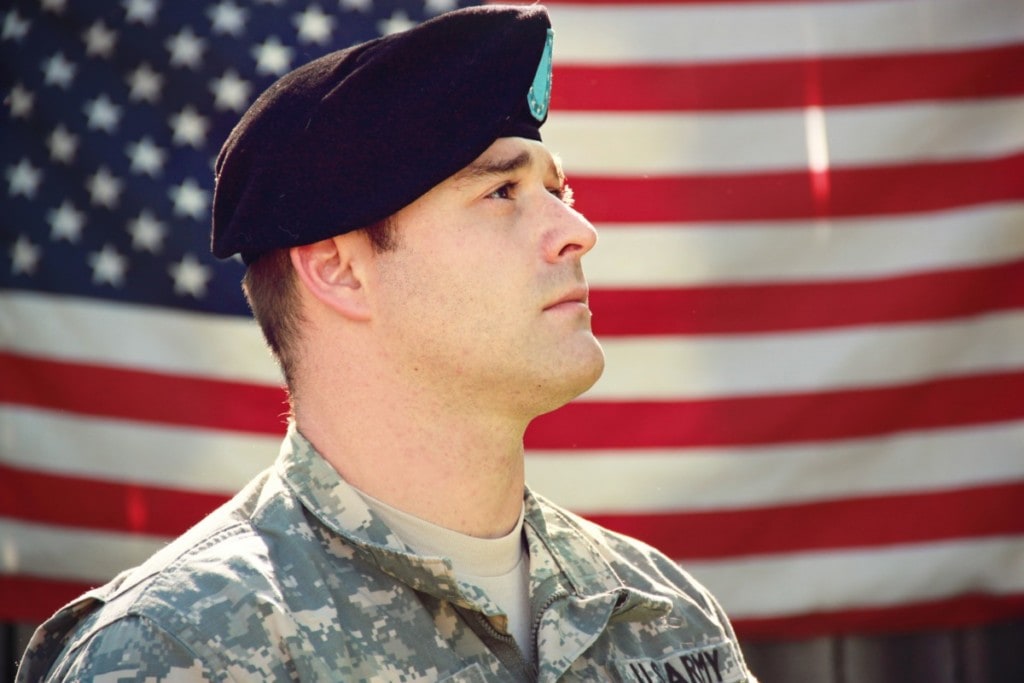 veteran in uniform in front of American flag