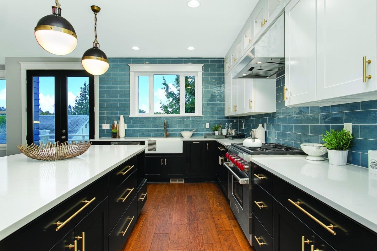 Kitchen with black cupboards, white countertop and blue tiled backsplash