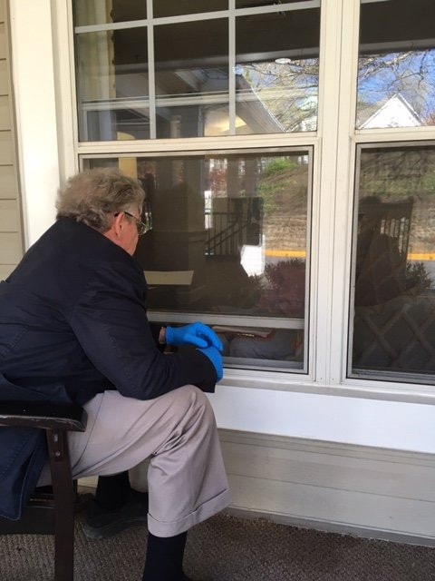 A Redfin customer, barely visible through the window of a long-term care facility, consults with a closing attorney. She cried tears of relief when her home sold.
