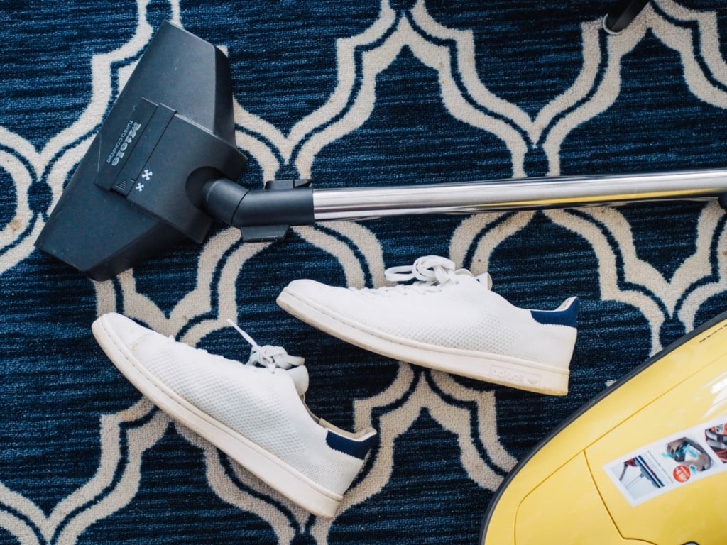 Shoes on the carpet next to a vacuum cleaning for indoor allergens