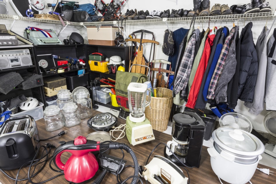 Cluttered spaced with items ranging from coats and shoes to a sled and a typewriter 