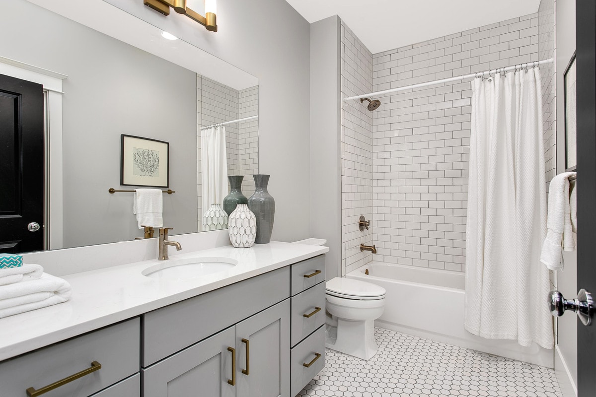 Full bathroom with white tiles and grey cabinets
