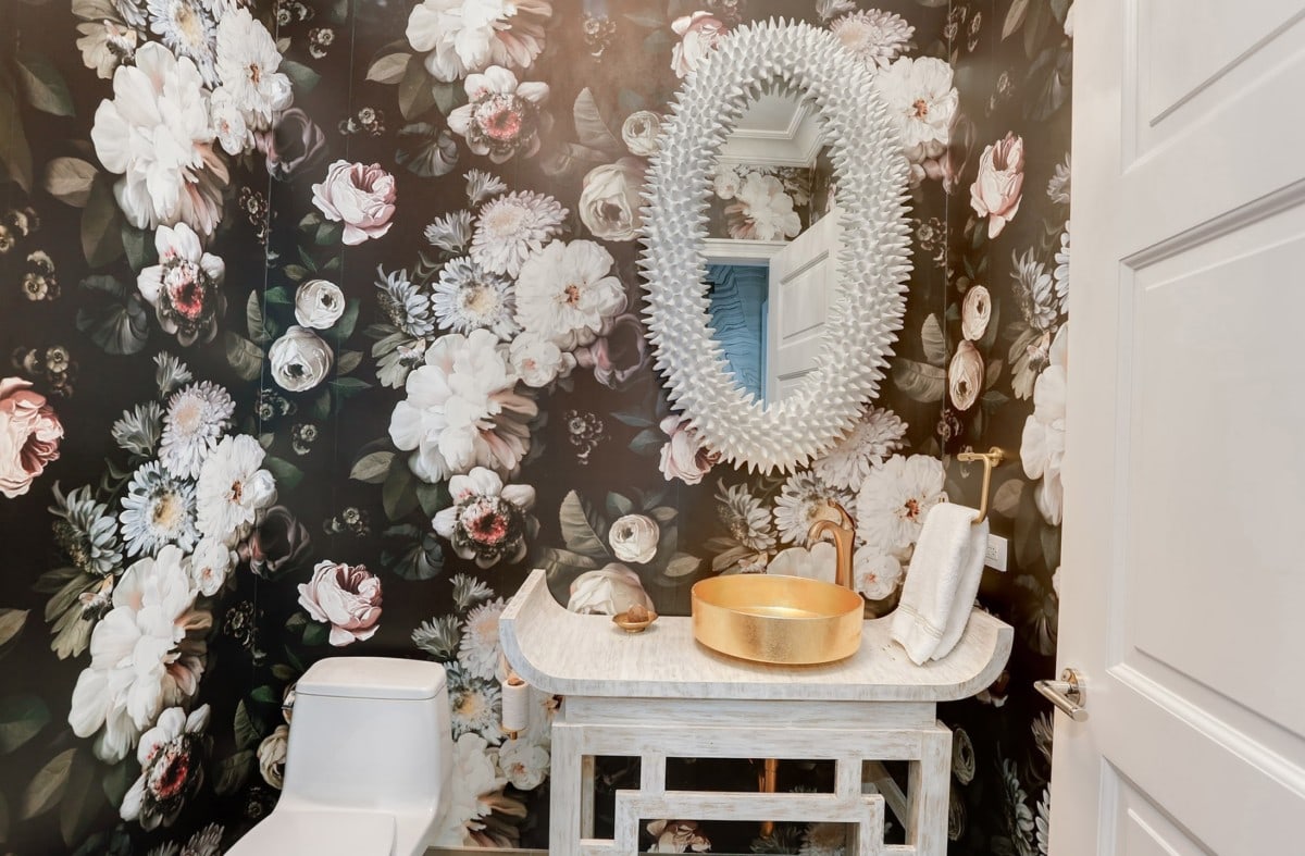 Funky floral wallpaper in a bathroom with a gold sink
