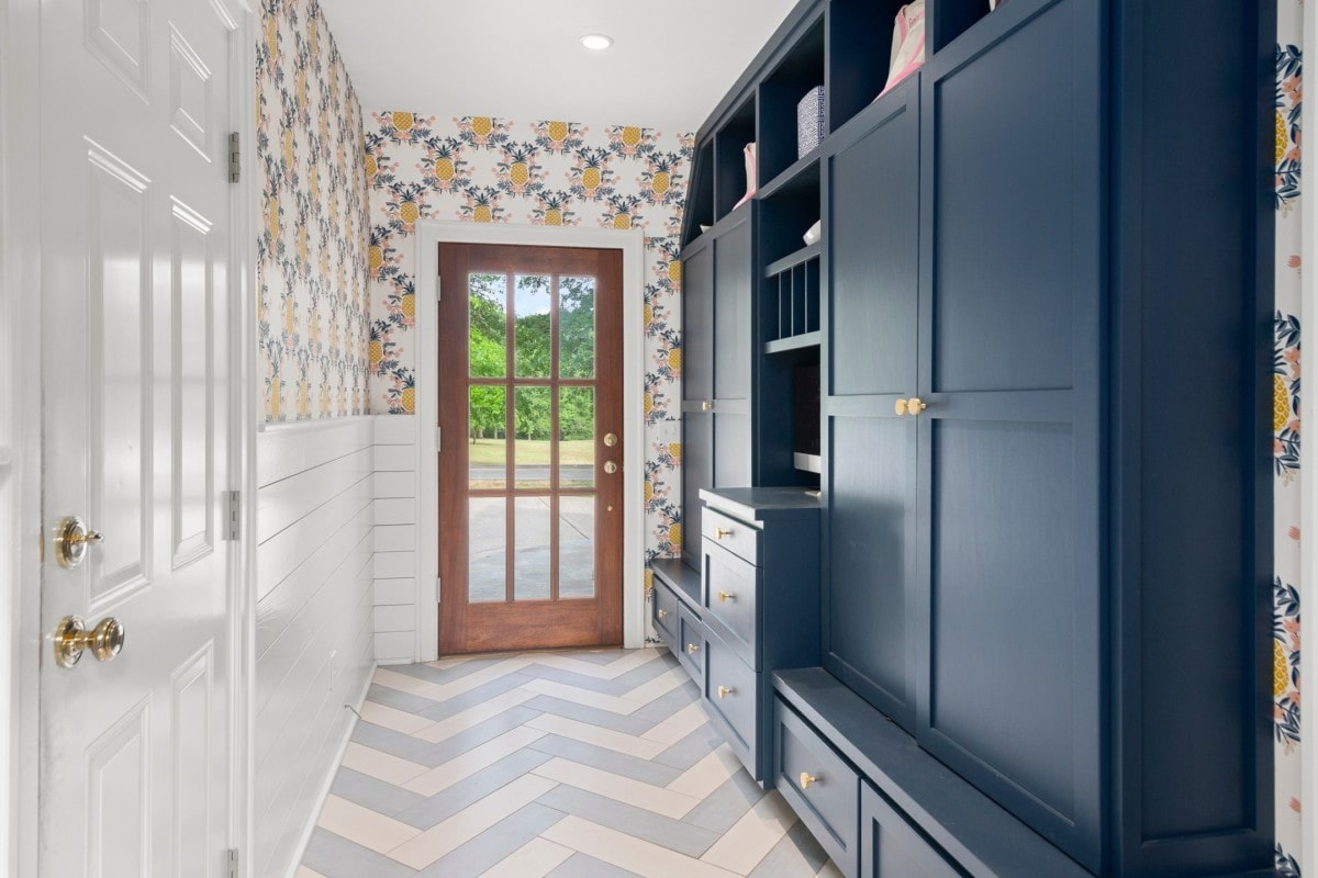 Pineapple wallpaper in the entryway of a home complementing the blue cabinets