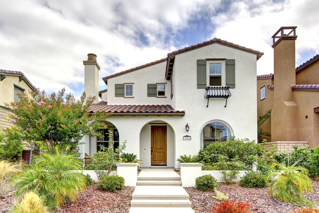Beige colored stucco home with green shutters