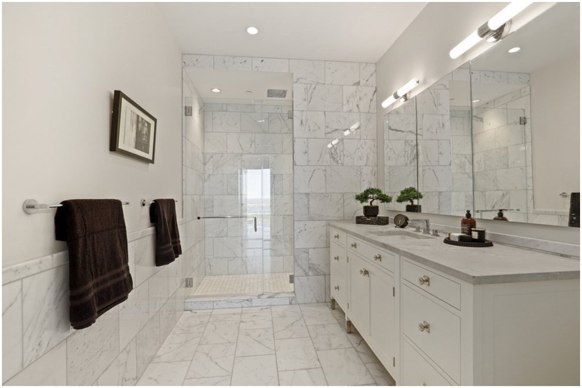 A white bathroom with a hinged shower door