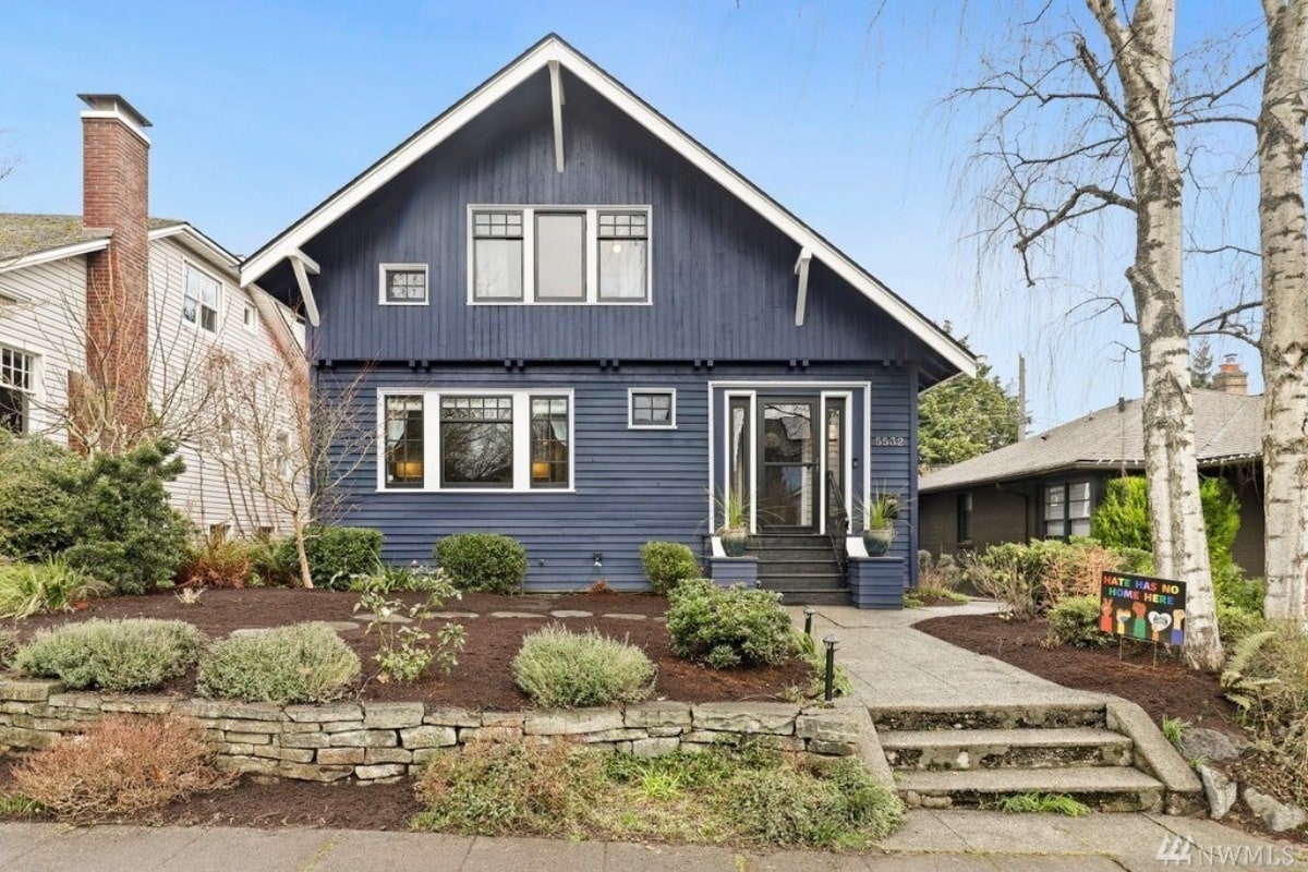 a blue house with beautiful shrubs and a storm door