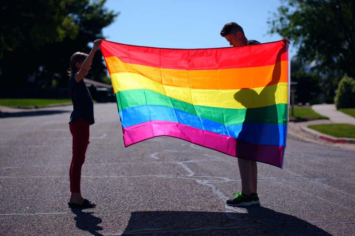 Two people holding up a Pride flag to show their support