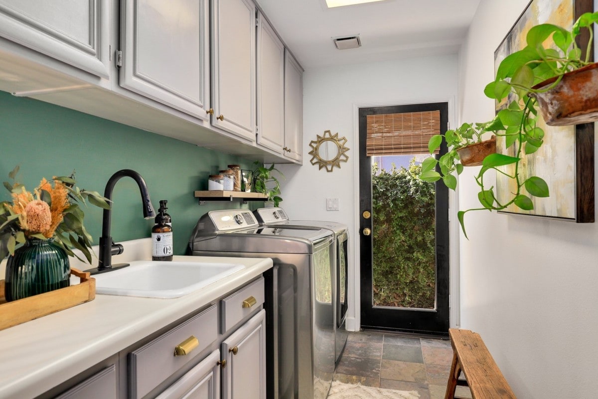 A laundry room with a exterior door and green painted accent wall