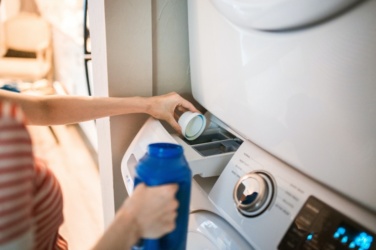 Woman pouring synthetic-free detergent into the washing machine is a laundry room hack
