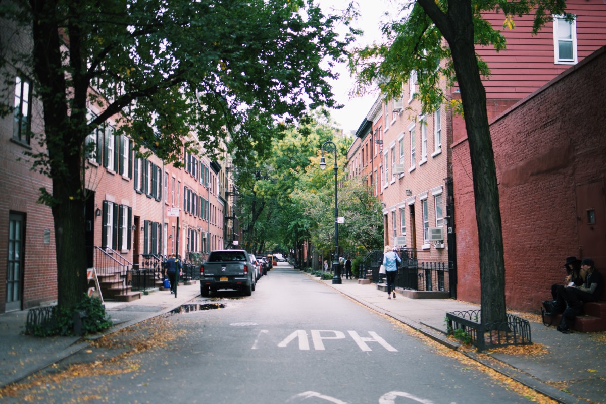 greek revival row house on a street with trees and cars