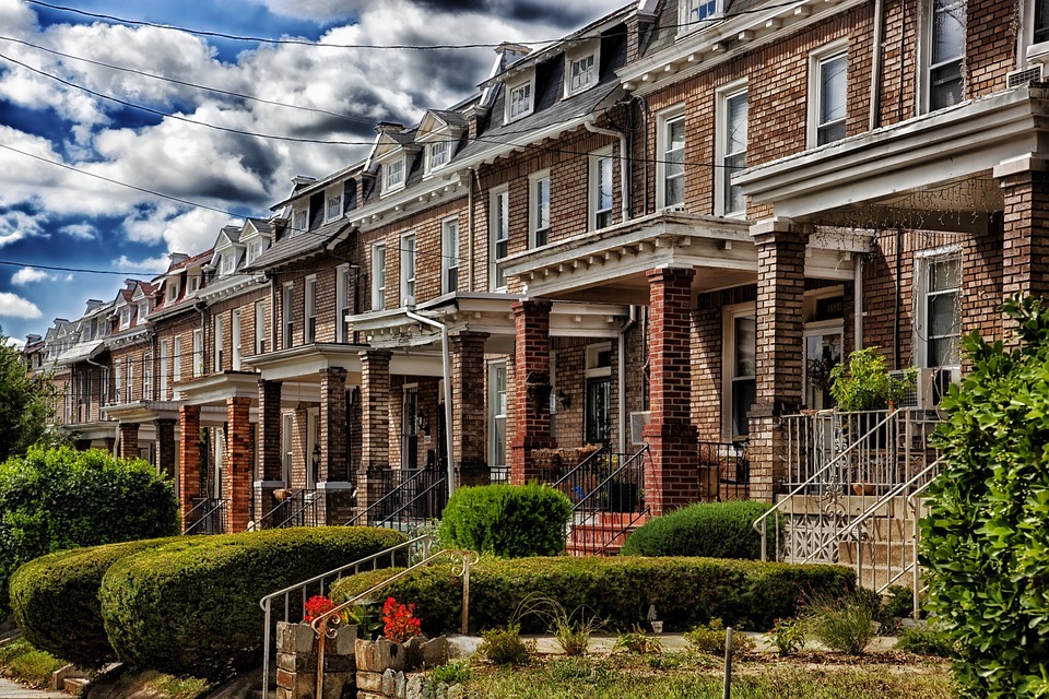 brick Georgian style row houses on a street with greenery