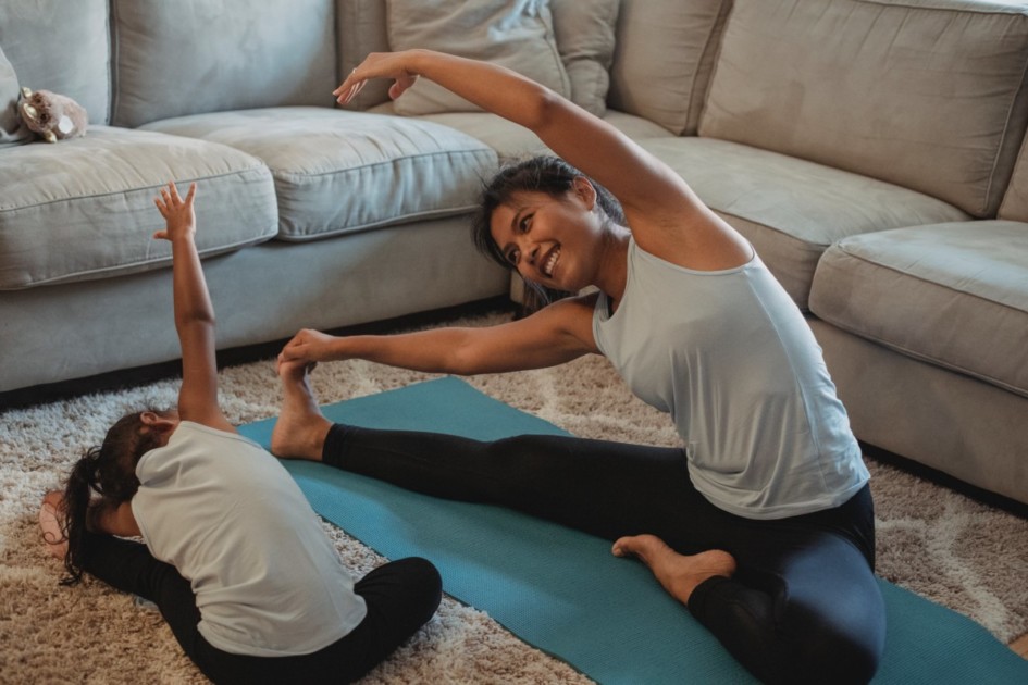 Mom and daughter doing yoga in front of the couch in the living room