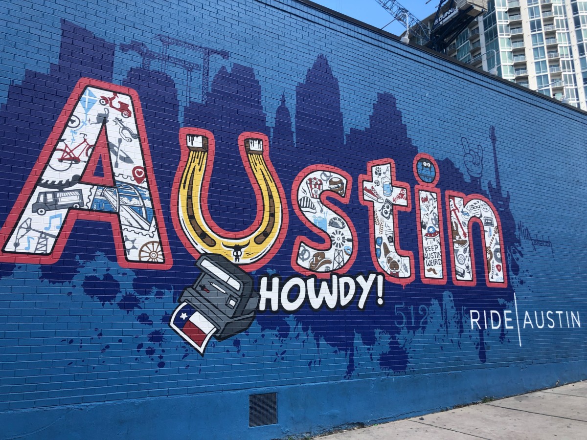 austin texas mural on a blue wall with howdy written on it