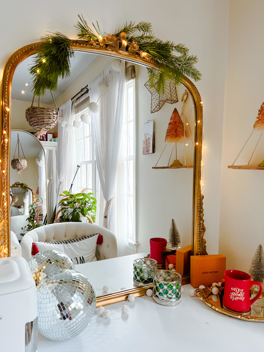 holiday living room decor with mirror, lights, white furniture, and trees