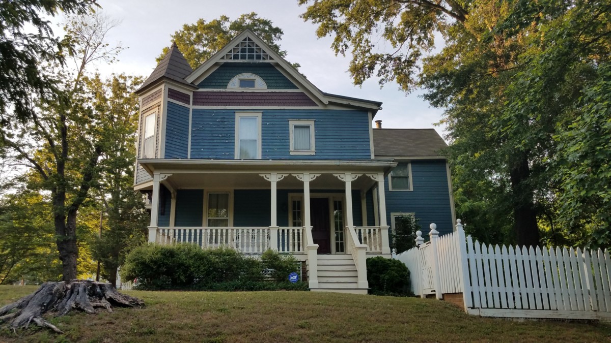 shingle style victorian house with blue paint and white front porch