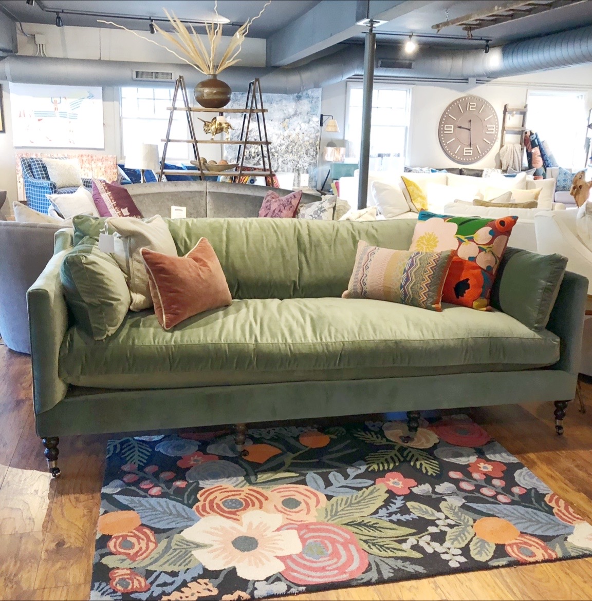 green couch with floral pillows and rug