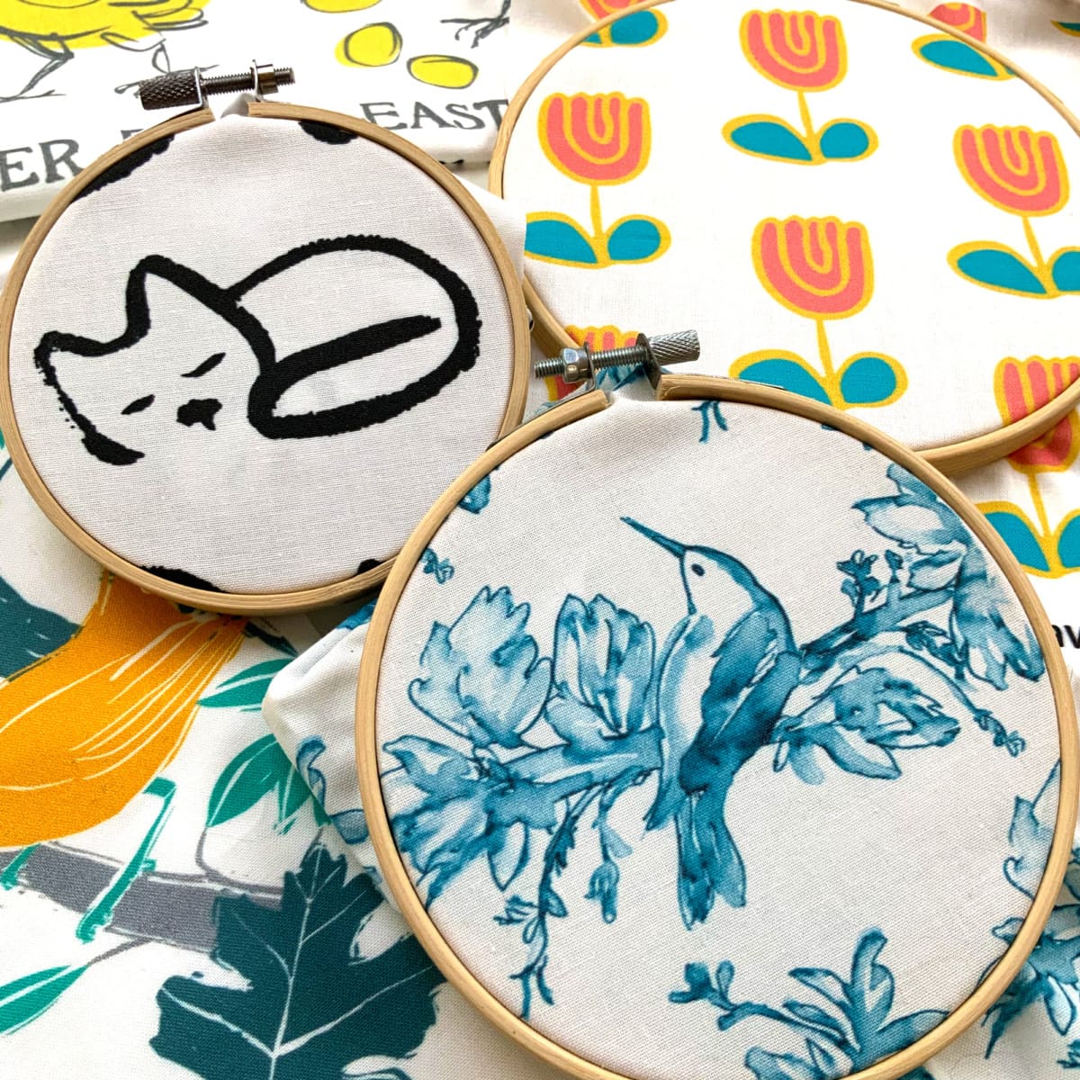 thread artwork with patterned cats, bird, and tulips