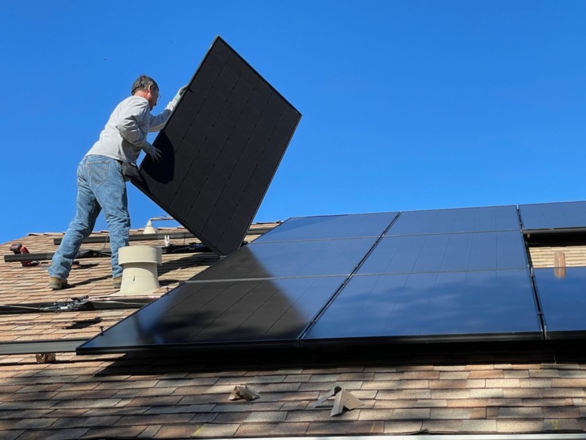 Man putting on solar panels to be more eco-friendly at home