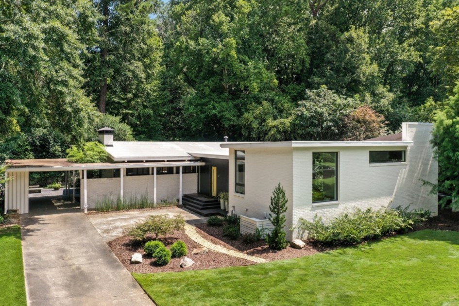 A white mid century modern home with a large yard