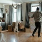 Two people moving boxes into a new apartment