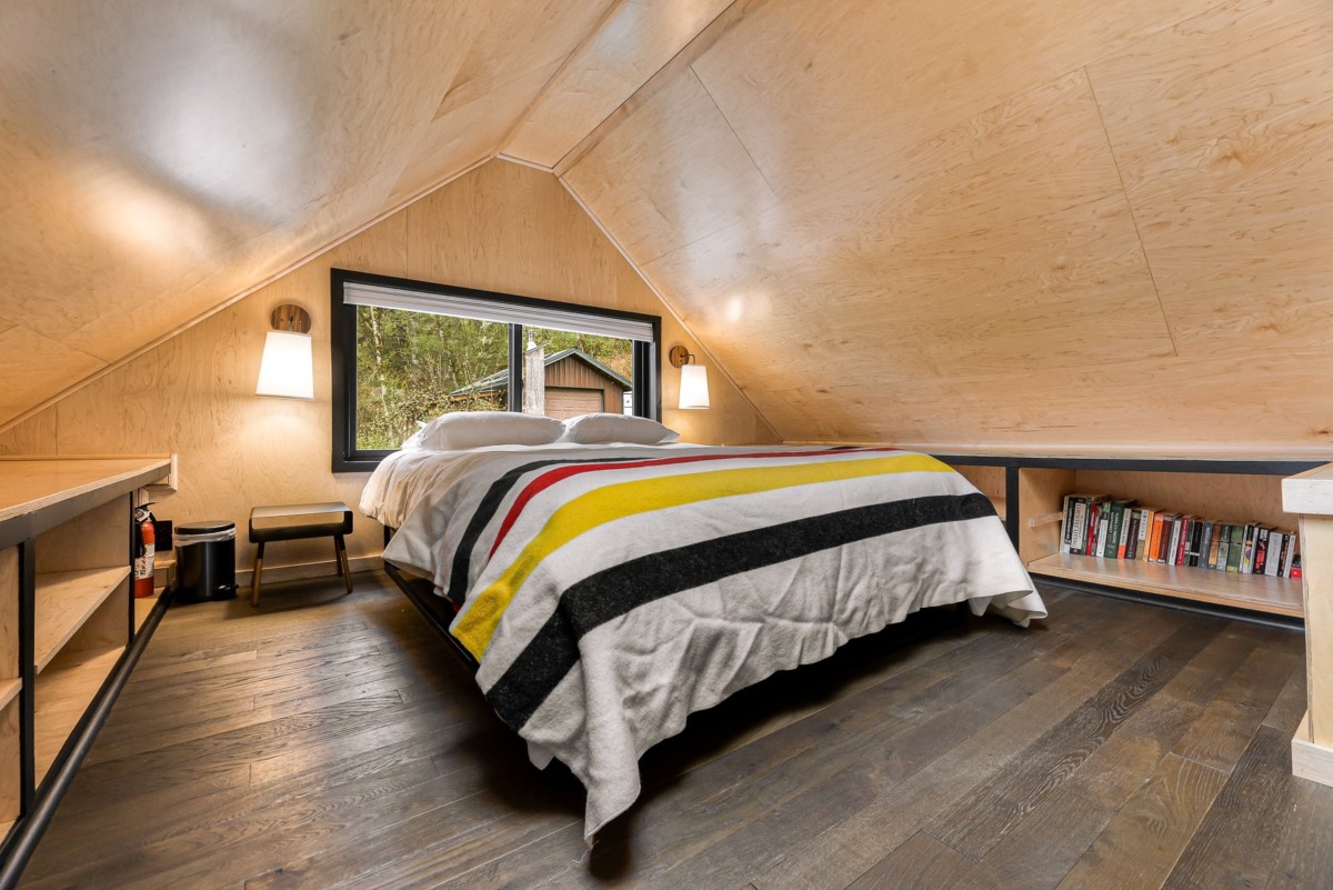 single bedroom at the top of an A frame house with cedar panels on the walls