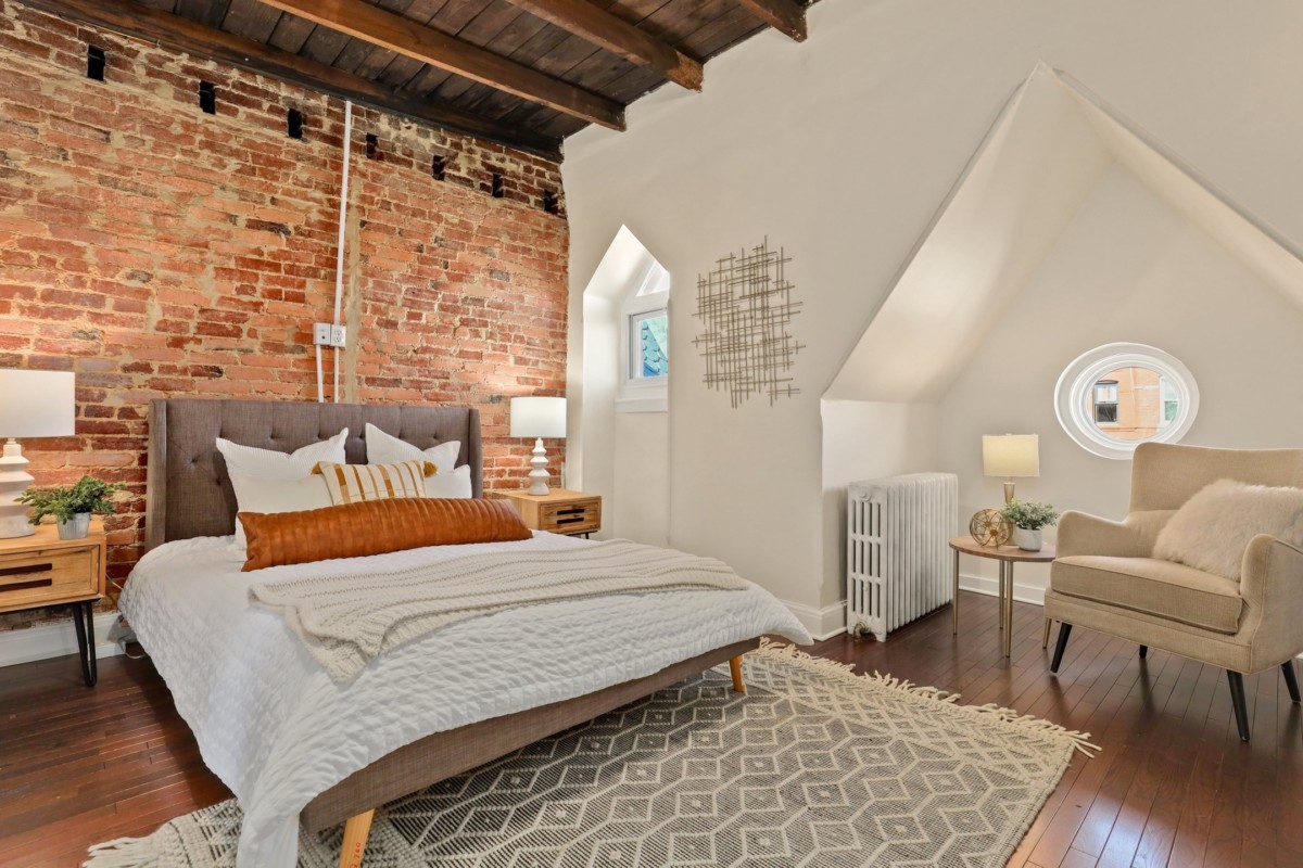 bedroom in an apartment with brick walls and small windows