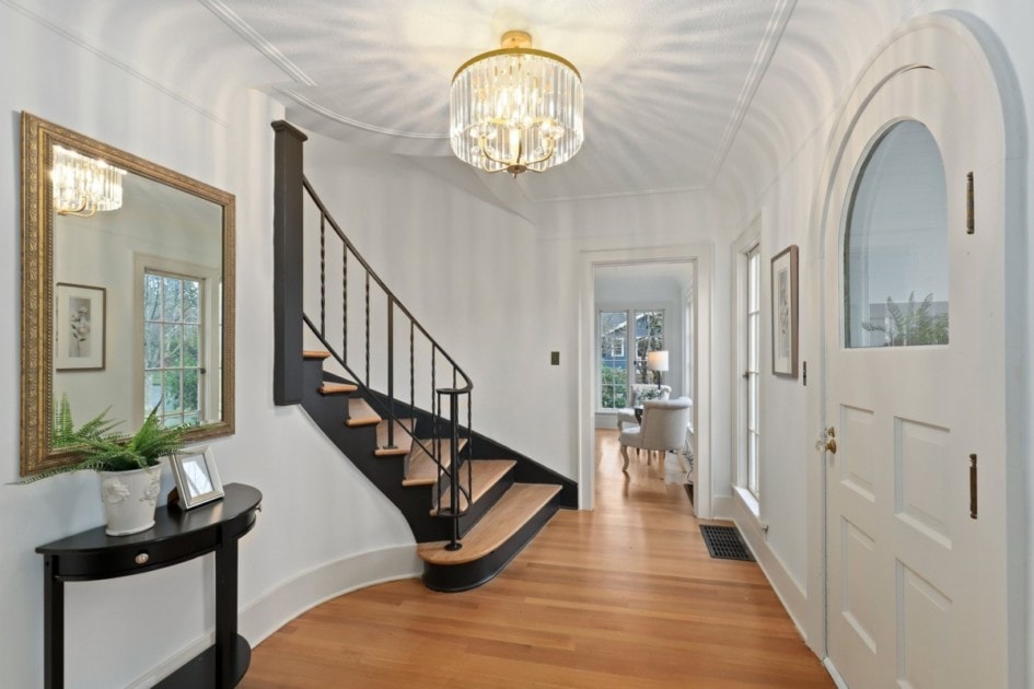 Entryway with arched front door, hardwood floor, and classic spiral staircase