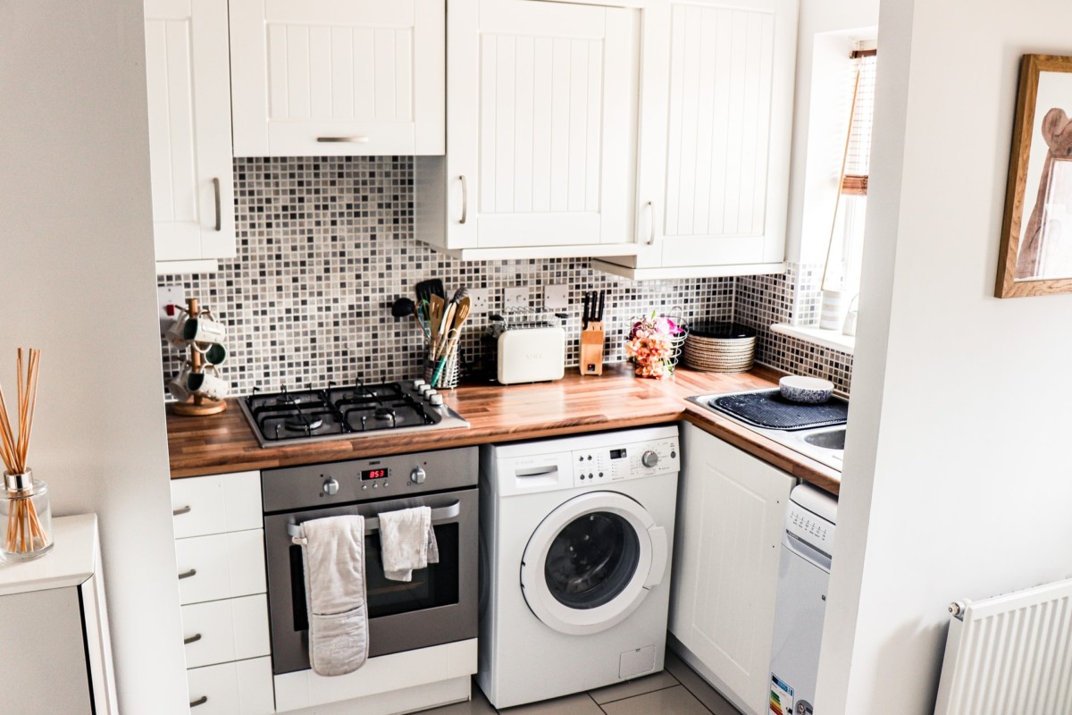 kitchenette with laundry machine and white cabinets