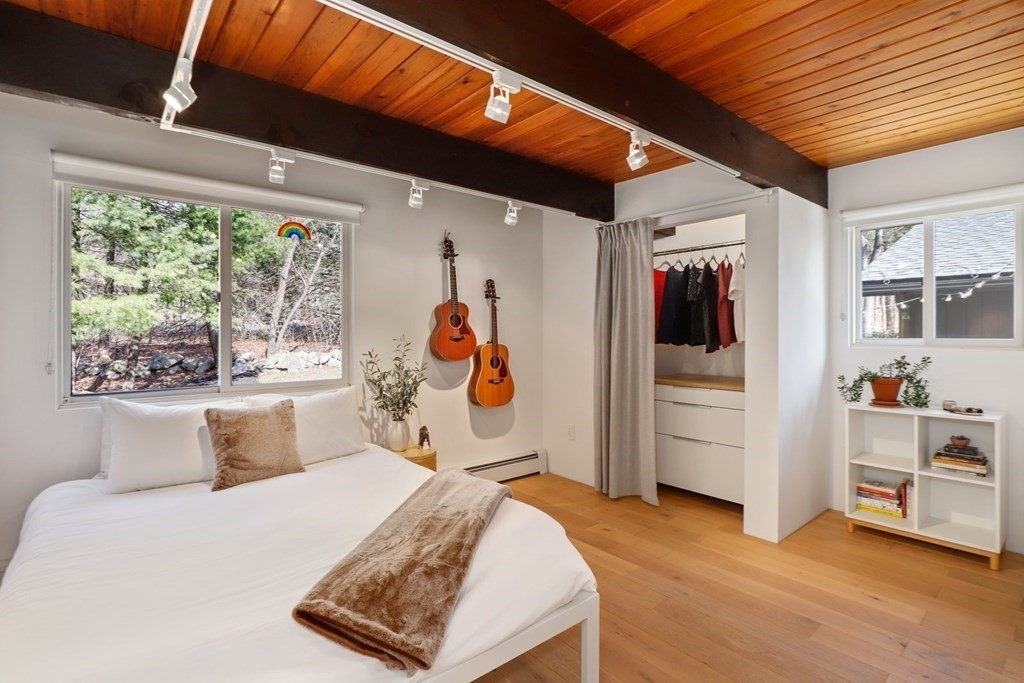 dormitorio principal en una casa de campo con vigas vistas, suelo de madera y vistas a la naturaleza