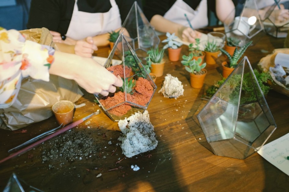 Group of radical   making terrariums with plants, moss, and dirt.