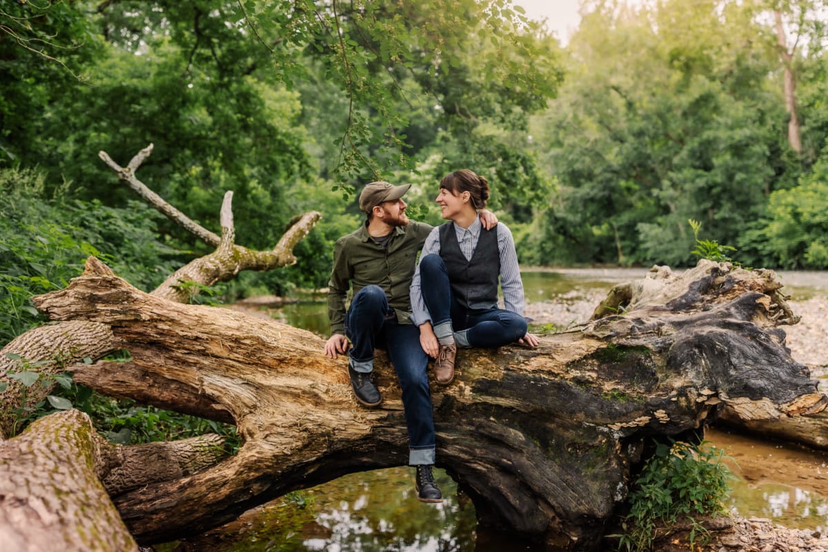 Um casal está sentado em um tronco na floresta