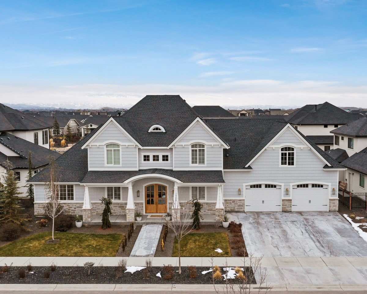 two story french country style home with white and brick exterior and large windows