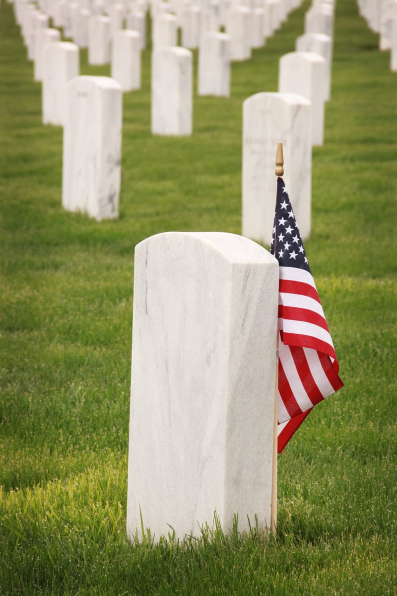 US flag standing near a tombstone 