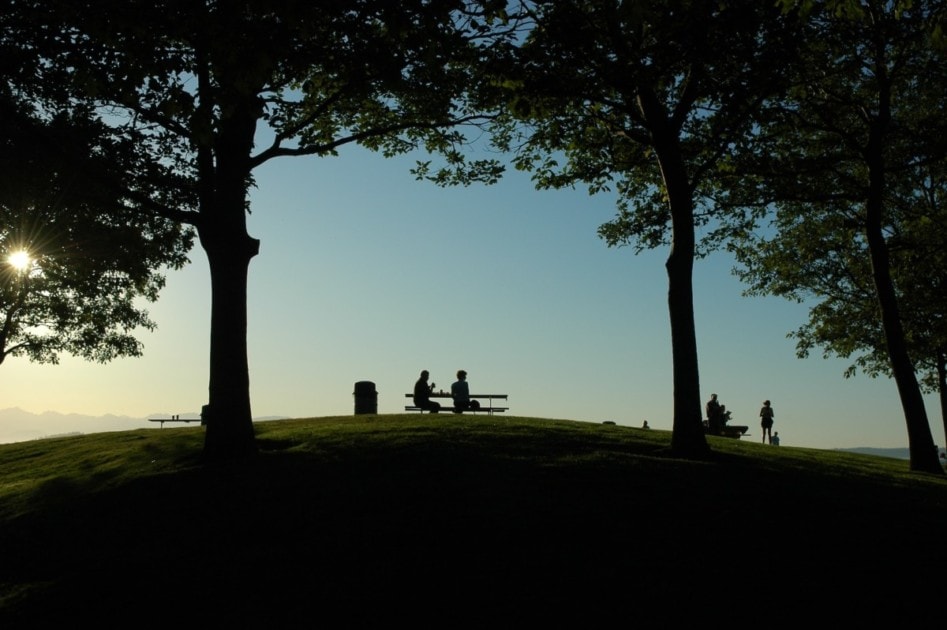 Two people sitting at a picnic bench at Discovery Park, one of the many parks Seattle is known for.