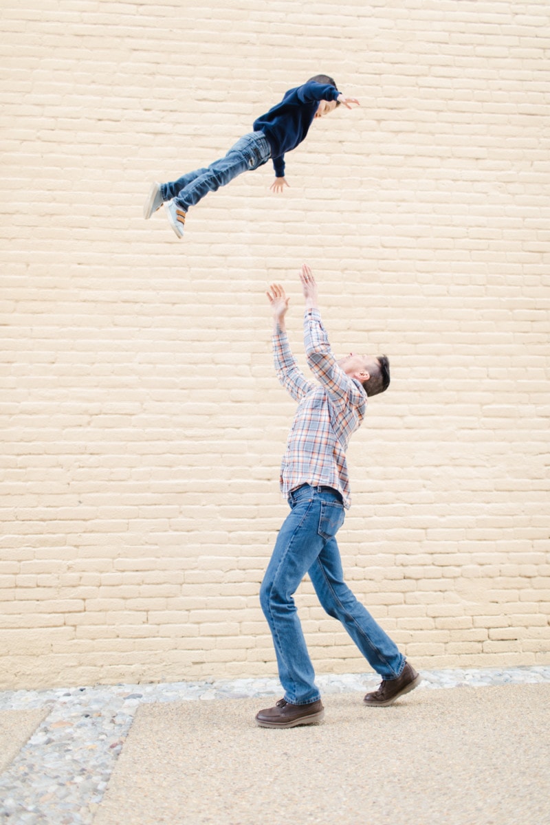 Father playing with his child in front of a brick wall