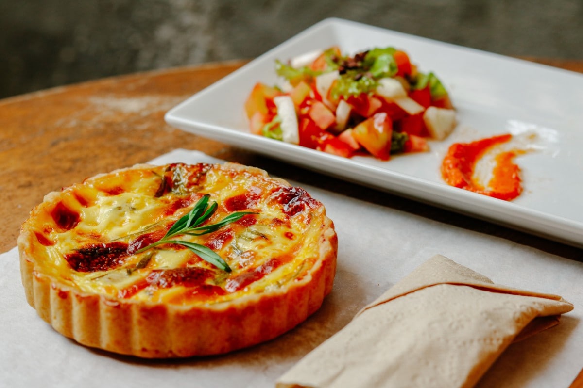 quiche dish on a table with veggie salad