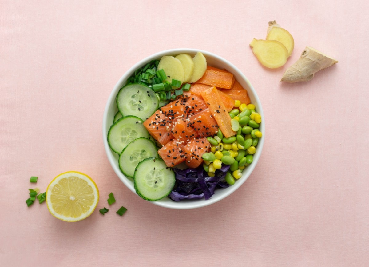 salmon poke bowl with veggies on a pink table