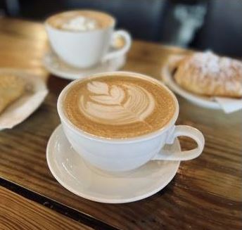 A cup of coffee with a design of a flower drawn into the froth