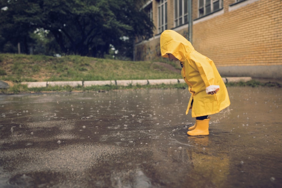 Small boy walking outdoors at rainy autumn day